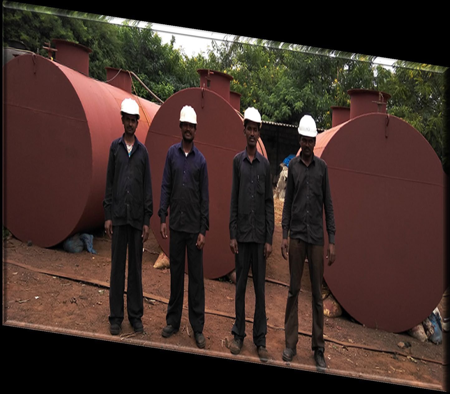 VSS Enterprises fabrication team in blue uniforms and hard hats standing in front of completed vertical storage tanks